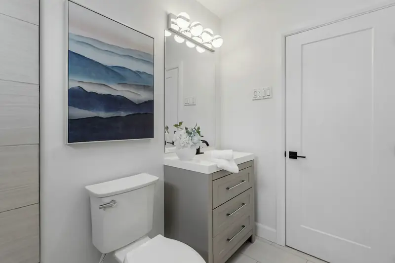 Compact white bathroom with a low toilet next to a gray vanity cabinet